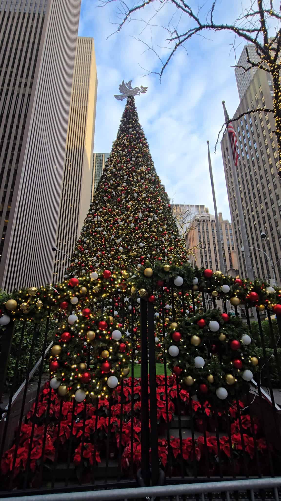 Outdoor tower Christmas tree adorned with gold, red and white ornaments.